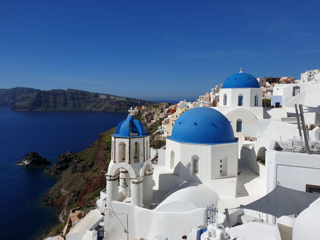 A blue domed church perched on a cliff in Oia village in Santorini