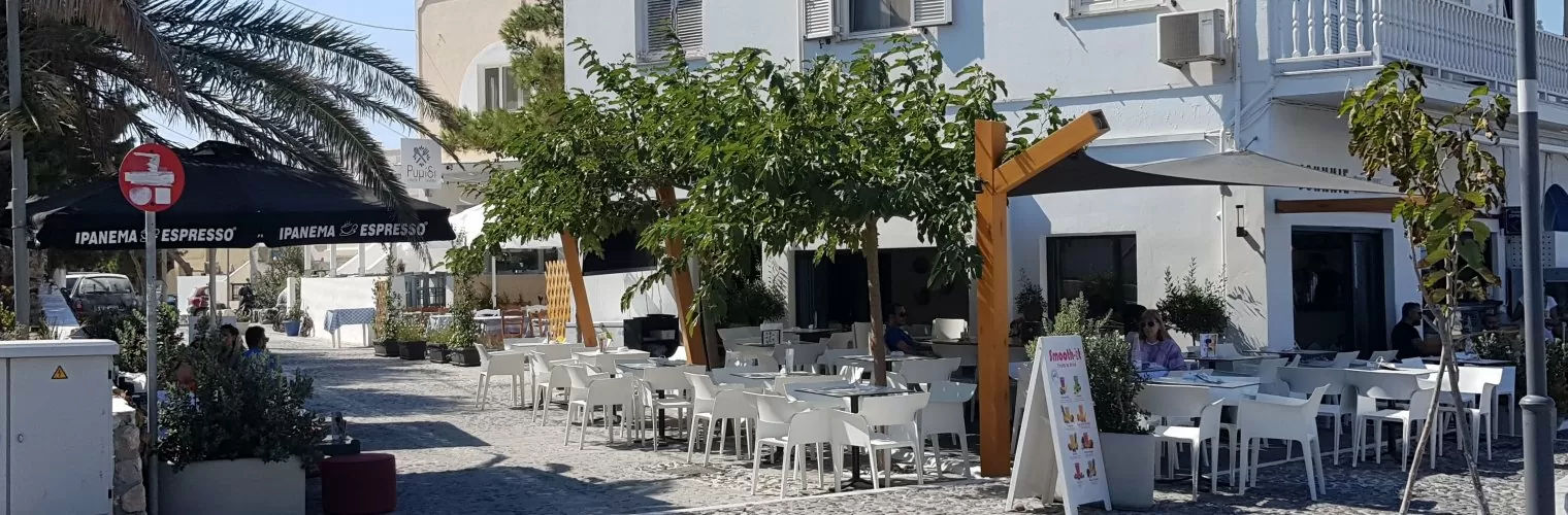 A cafe with white chairs on a cobbled street in Santorini