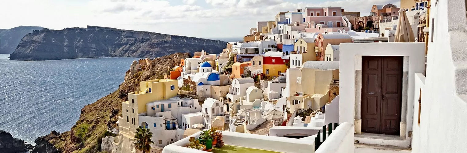White-washed and colored buildings perched on a caldera cliff in Santorini