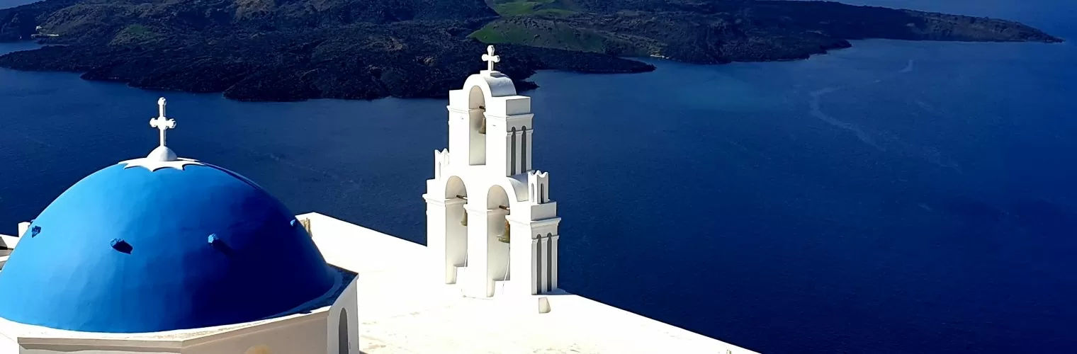 Blue-domed church with Aegean sea as a background