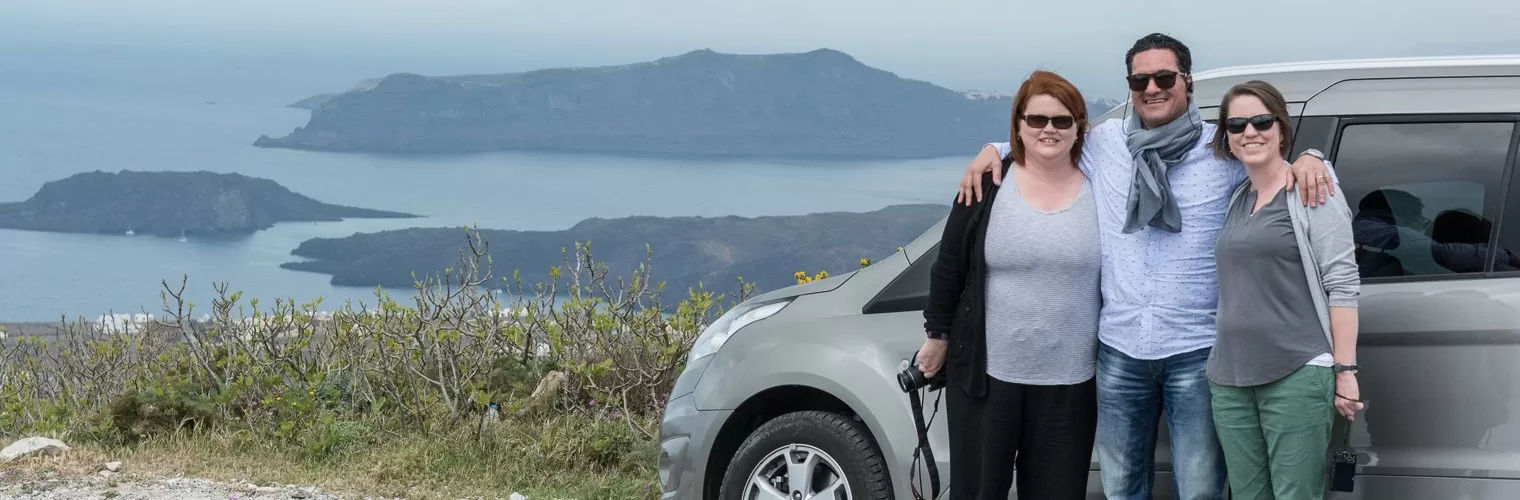 3 people in front of a car posing while having the Aegean sea as a background