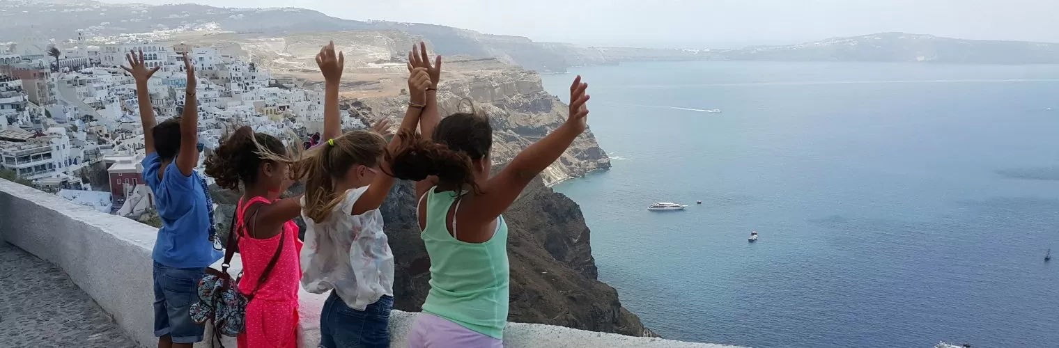 Kids posing with their hands open overlooking the Santorini caldera