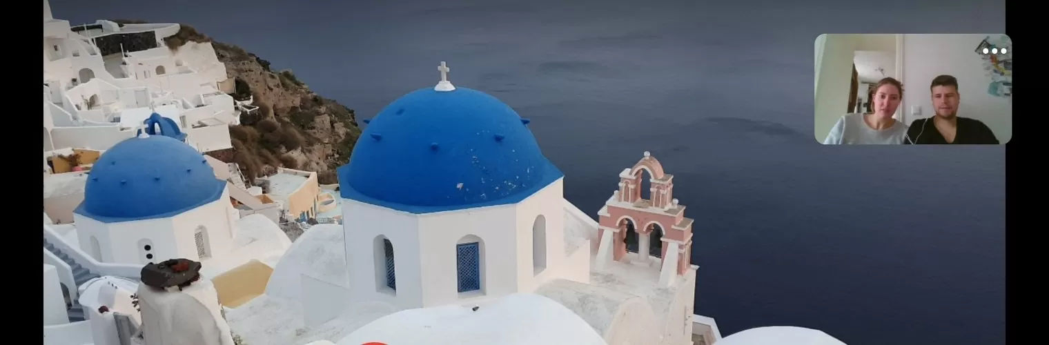 Screenshot of a couple watching the island sights during a Santorini live sunset virtual tour