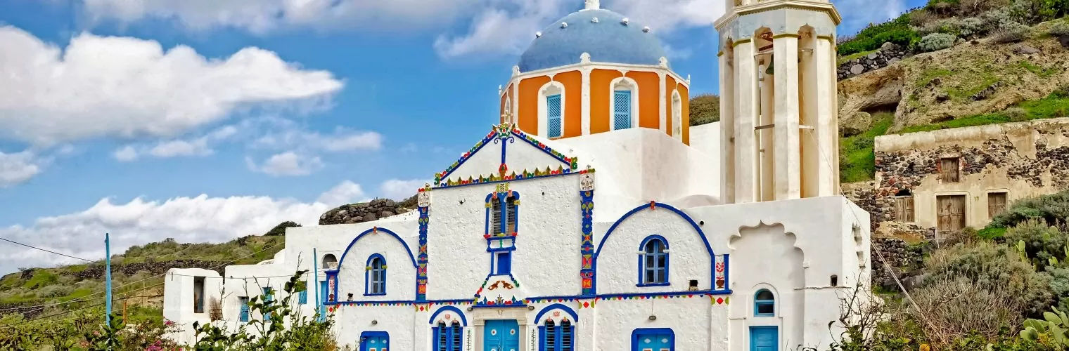 A white-washed church with orange-blue dome you see during the Thirassia day trip from Santorini