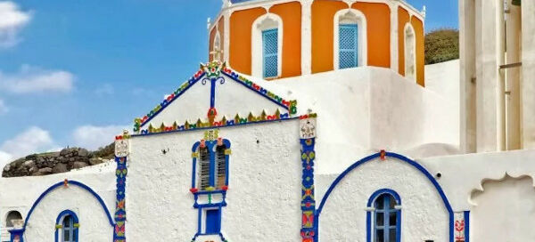 A white-washed church with orange and blue dome you see in the Thirassia day trip from Santorini