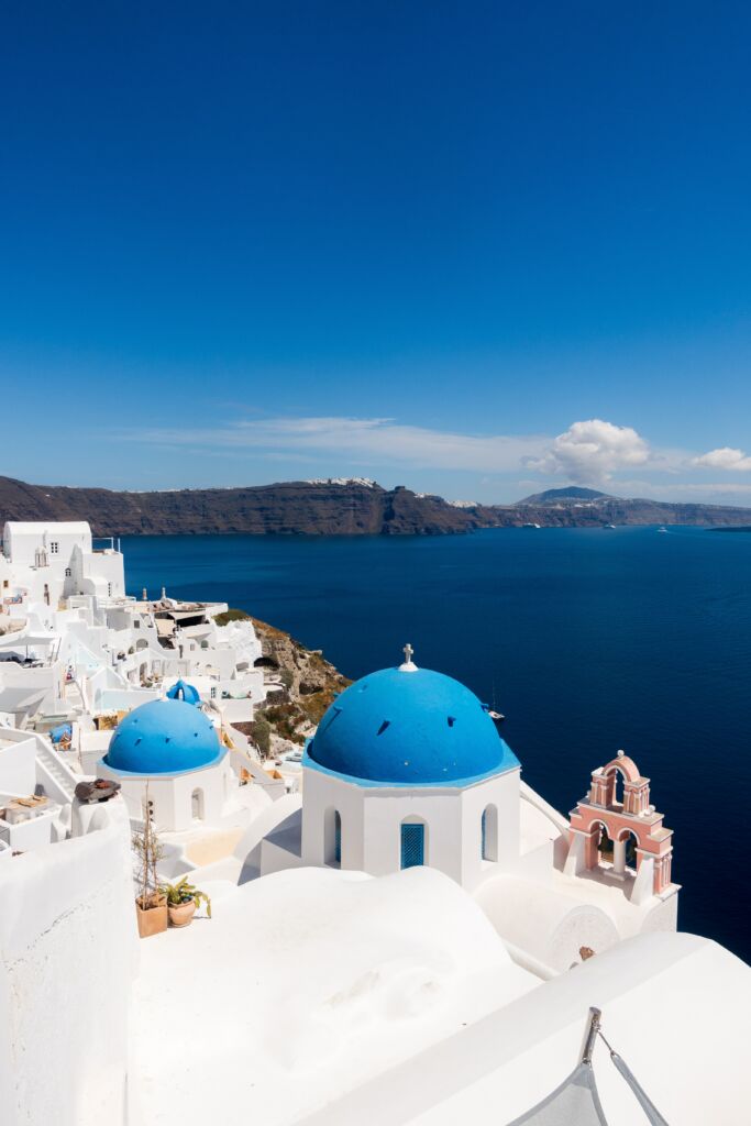 A Santorini blue-domed church with the Aegean Sea in the background