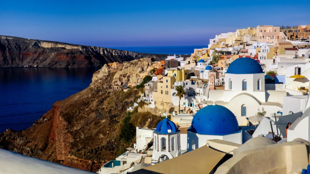 White-washed churches with blue domes perched on the Santorini caldera