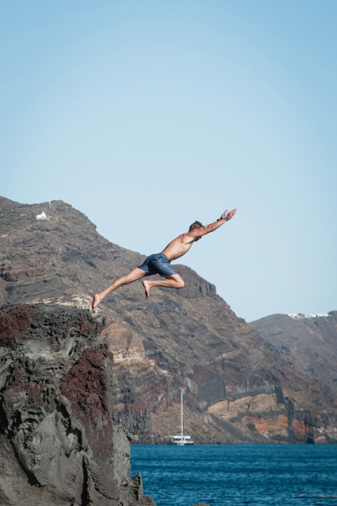 A man jumping of a volcanic cliff in Santorini