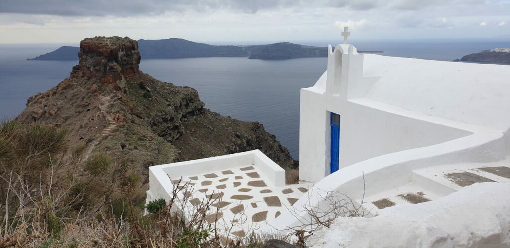 Whitewashed chapel with Skaros Rock in the backdrop - Santorini in winter